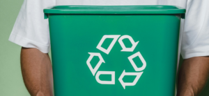 Lixeira verde com o símbolo da reciclagem em destaque.